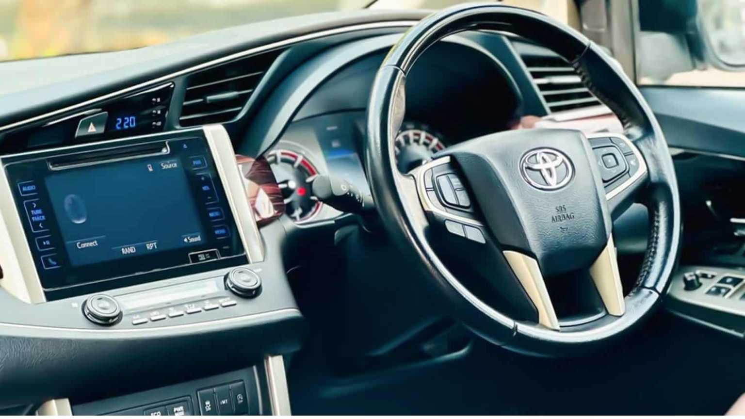 The Toyota Innova Crysta's dashboard and steering wheel are designed for comfort and safety, important for our Madurai cab booking service.