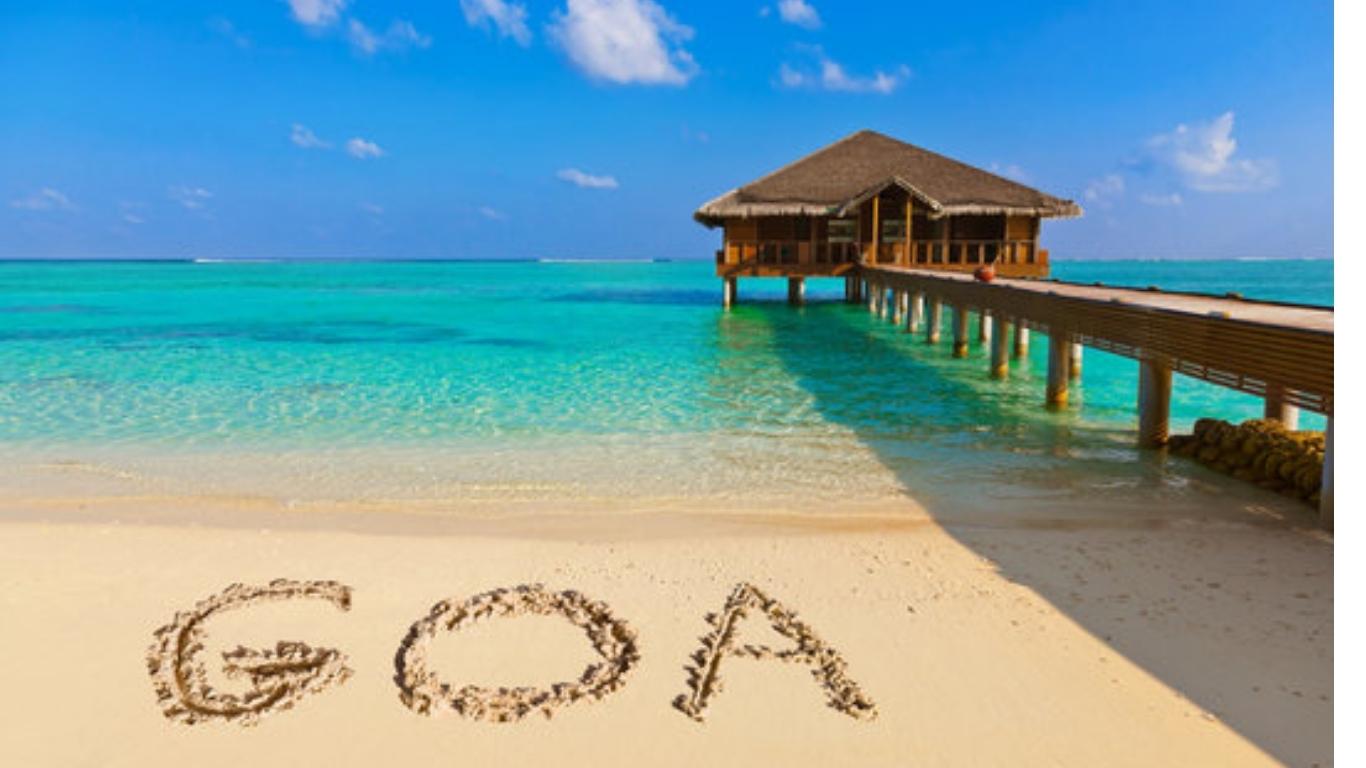 A Goa beach with clear blue water, a pier, and the word GOA written in the sand – perfect for Madurai to Goa cab tour packages.